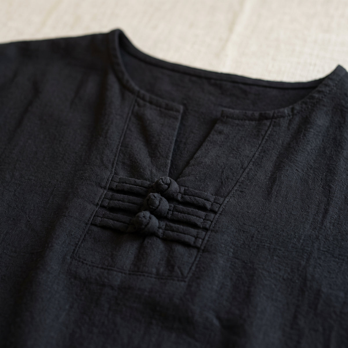 Encolure en V et ses trois nœuds de tissu sur l'ensemble noir, en gros plan