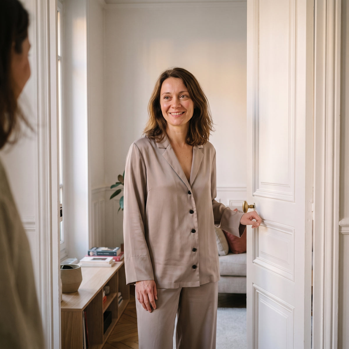 Femme en pyjama de satin beige qui ouvre la porte de son appartement Image