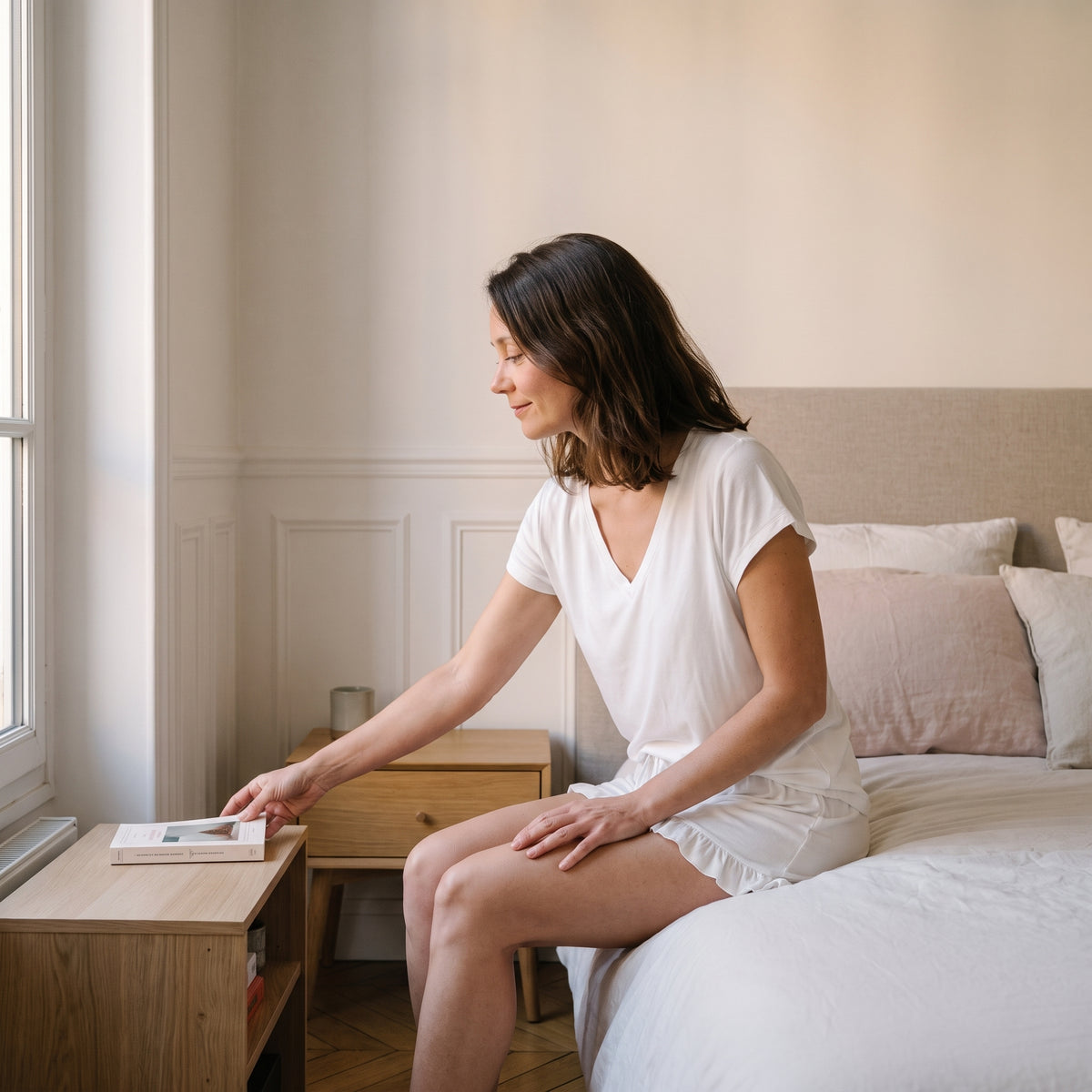 Femme assise sur son lit en pyjama léger deux pièces blanc Image