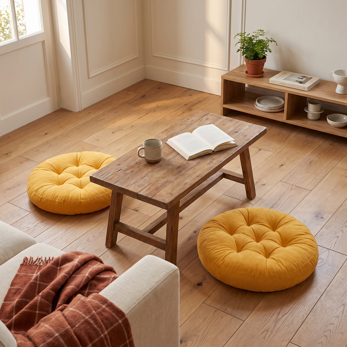 Deux coussins de sol jaune moutarde de part et d'autre d'une table basse, une tasse et un livre ouvert Image