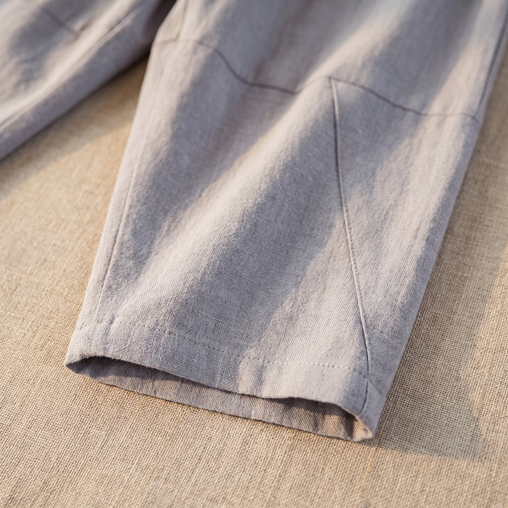 Ourlet et découpe en biais du bas de jambe du pantalon gris, en gros plan