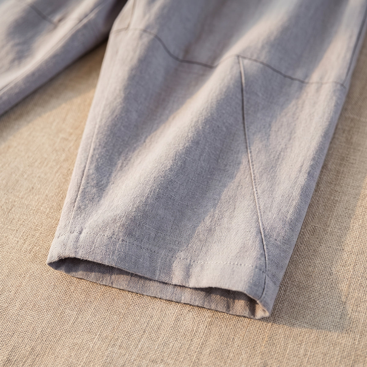 Ourlet et découpe en biais du bas de jambe du pantalon gris, en gros plan