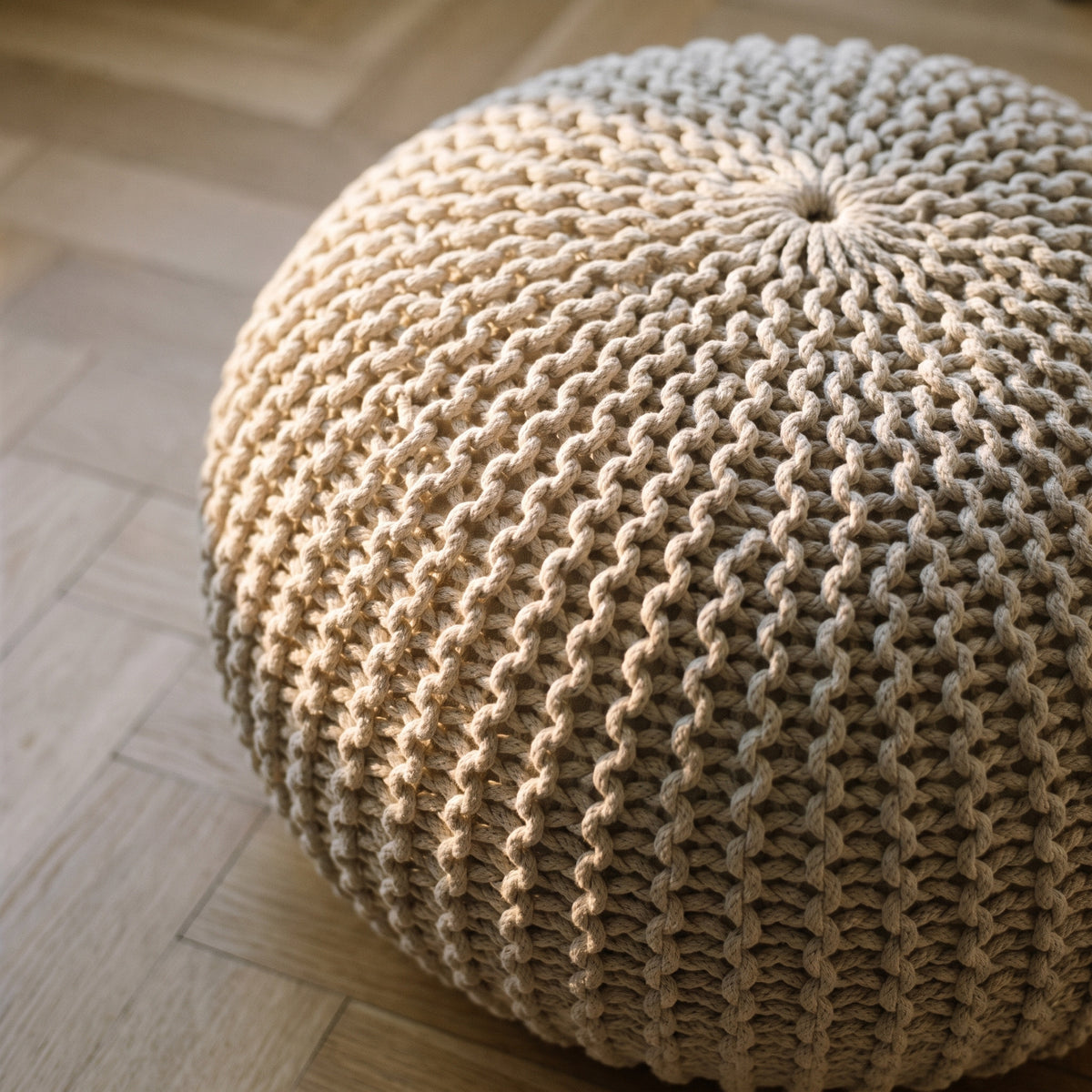 Dessus du pouf écru vu en plongée : la spirale des rangs monte du bord jusqu'à la petite couronne qui ferme le tricot au sommet Image