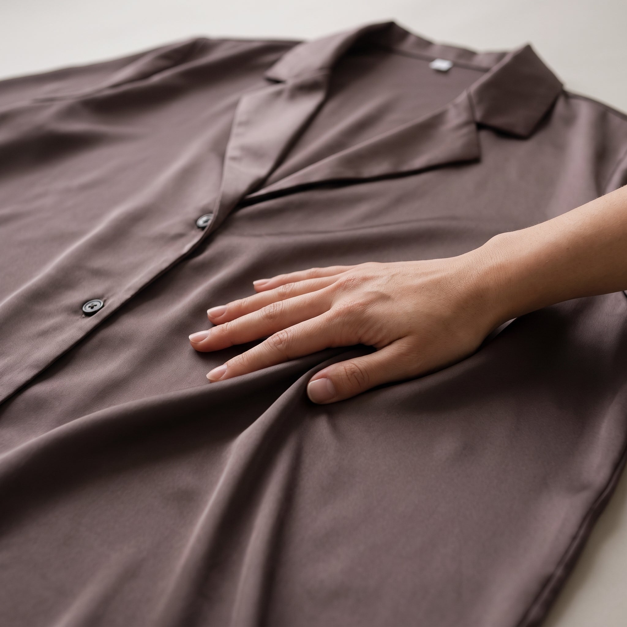 Une main posée à plat sur le satin de la chemise, reflet du tissu Image