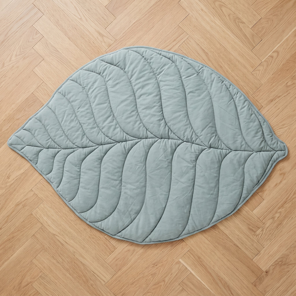 Tapis en forme de feuille vert d'eau vu du dessus, découpe entière à plat sur le parquet