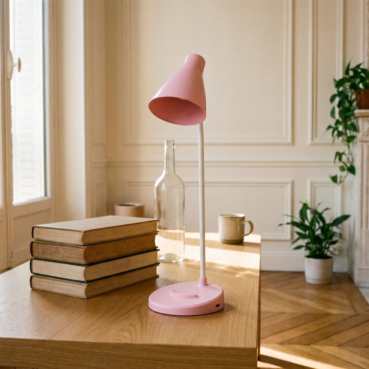 La lampe rose bras droit sur une table en chêne, à côté d'une pile de quatre livres reliés qu'elle dépasse de près de trois fois. Image