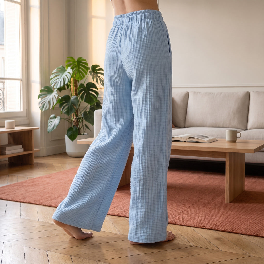 Pantalon large du pyjama kimono bleu ciel, de la taille élastique jusqu'au sol, pieds nus sur un parquet en point de Hongrie