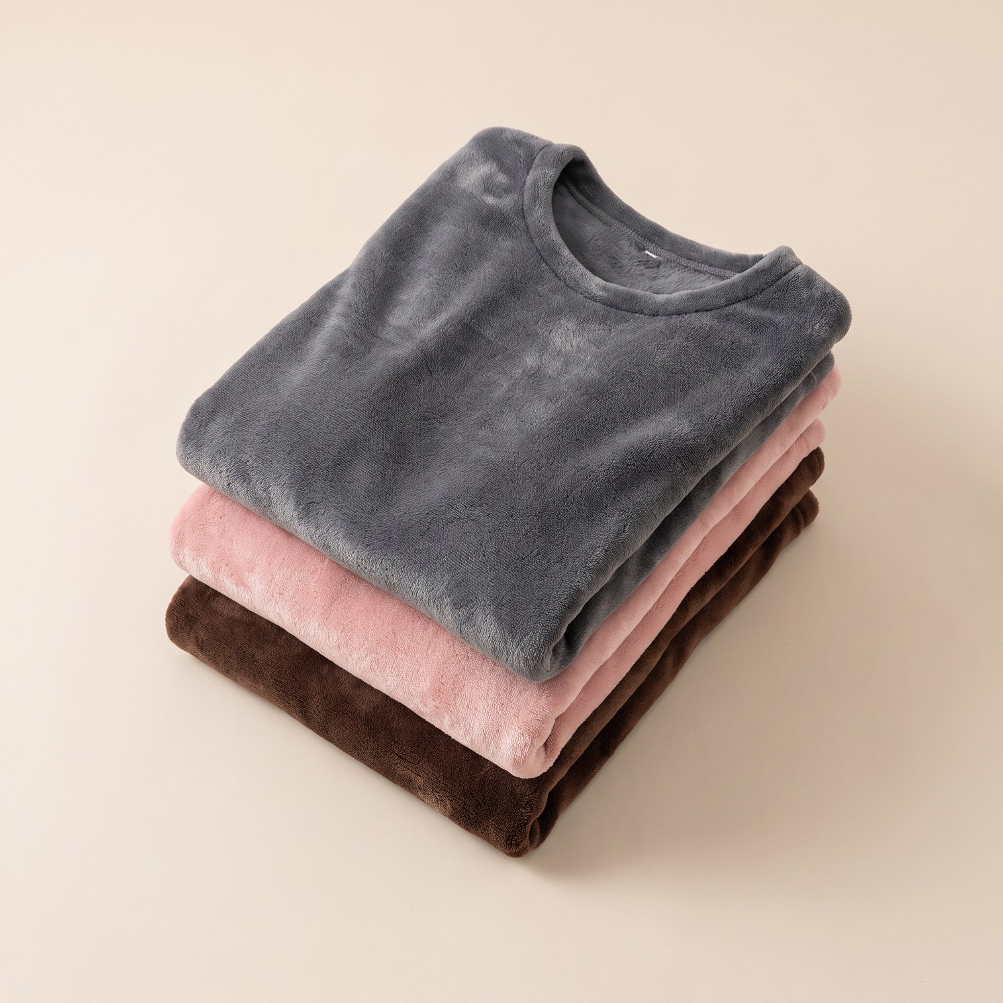 Trois pyjamas en flanelle polaire pliés en pile, brun chocolat, vieux rose et gris foncé Image