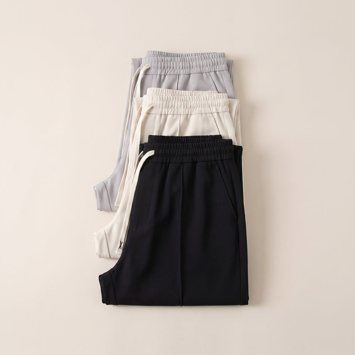 Trois pantalons d'intérieur fluides pliés en pile, noir, écru et gris perle Image