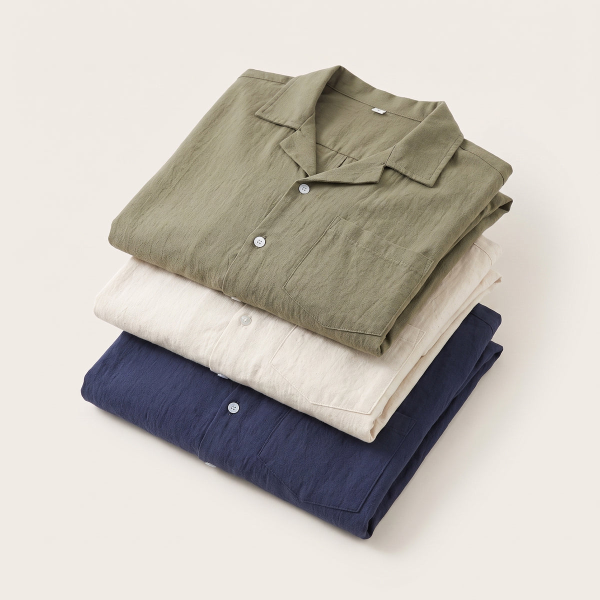 Trois ensembles chemise et short pliés en pile, kaki, écru et bleu marine Image