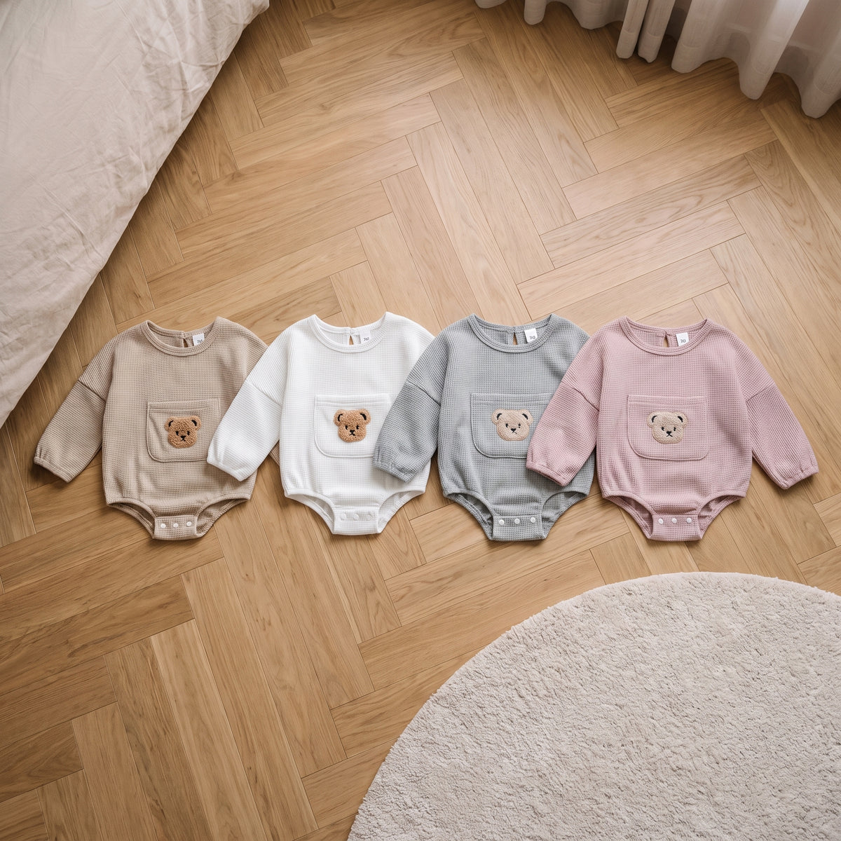 Les quatre coloris de la barboteuse bébé ourson : beige, blanc, gris et rose