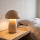 Lampe champignon en bois clair, grand modèle, allumée sur une table de chevet