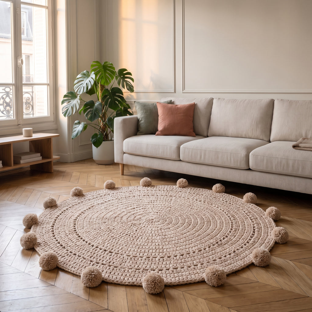 Tapis rond beige à pompons posé devant un canapé dans un salon
