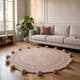 Tapis rond beige à pompons posé devant un canapé dans un salon