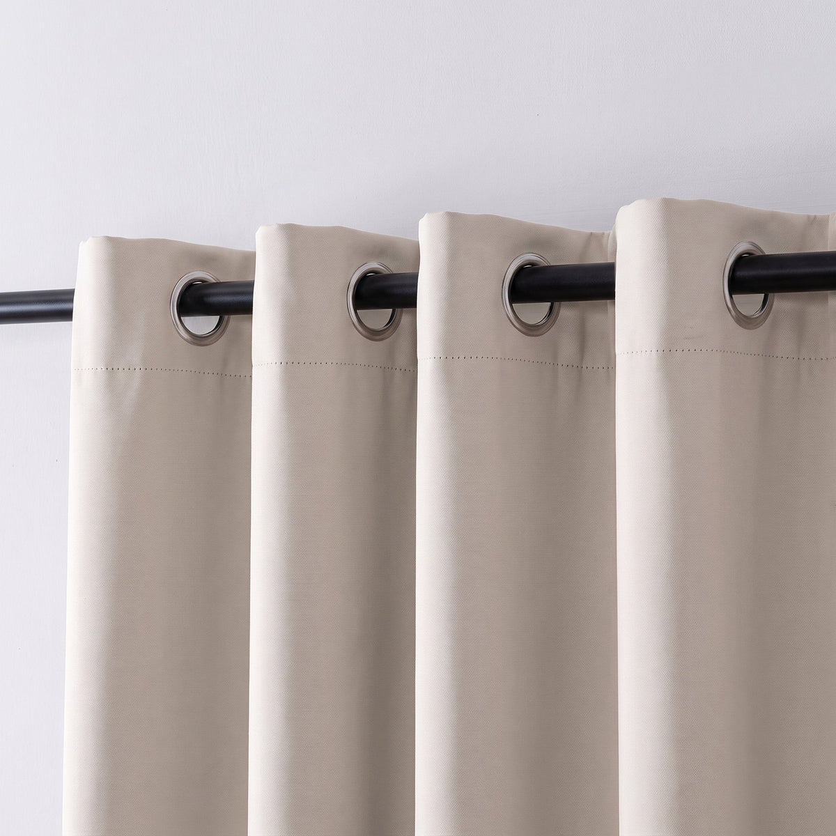 Tête à œillets d'un rideau occultant uni beige sur une tringle noire