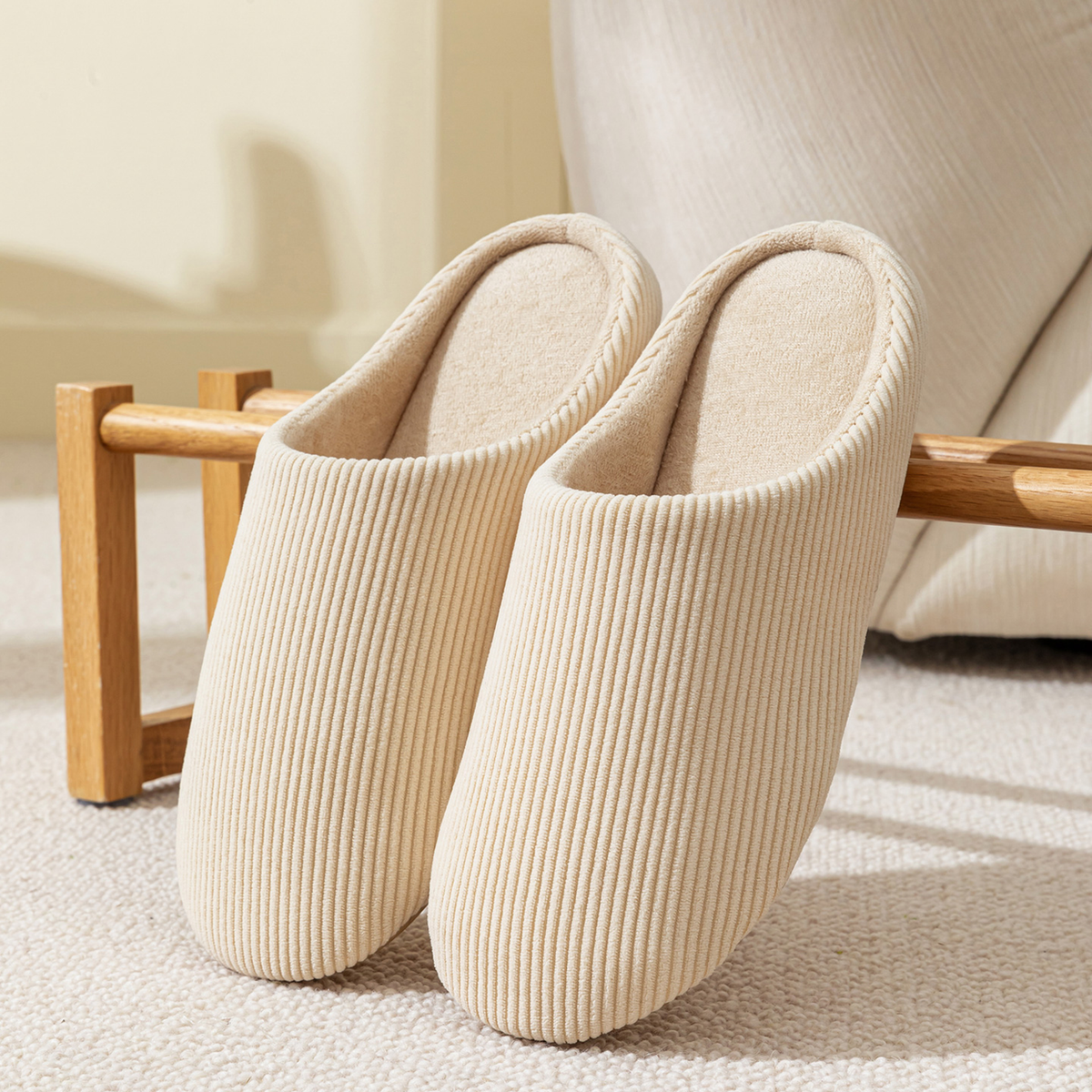 Paire de chaussons homme beige en velours côtelé posée dans un salon chaleureux