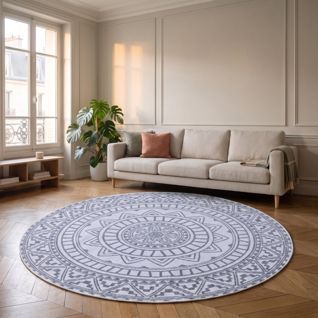 Tapis rond mandala blanc délavé et gris posé devant un canapé dans un salon