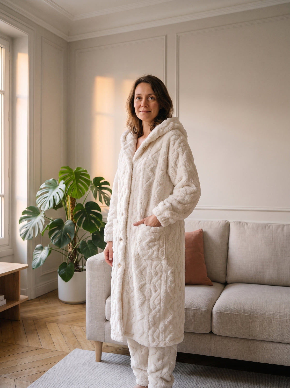 Femme châtain du casting Moment Cocooning portant l'ensemble pyjama blanc avec peignoir à capuche dans le salon