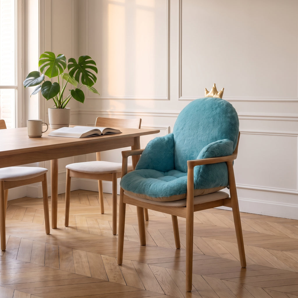 Coussin de chaise bleu avec petite couronne, installe sur une chaise en bois du coin repas