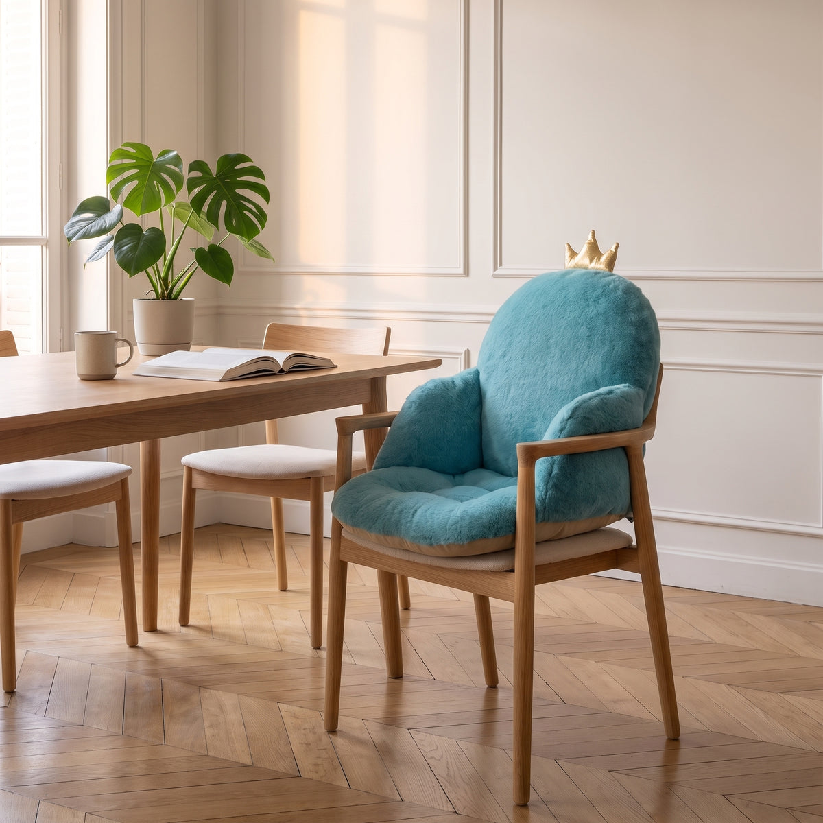Coussin de chaise bleu avec petite couronne, installe sur une chaise en bois du coin repas