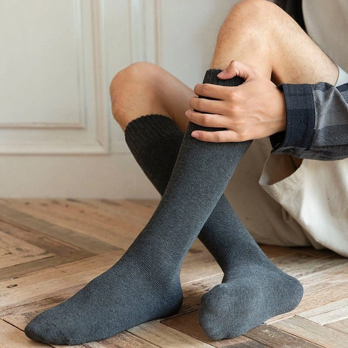 Chaussettes hautes gris foncé portées assis sur un parquet Image