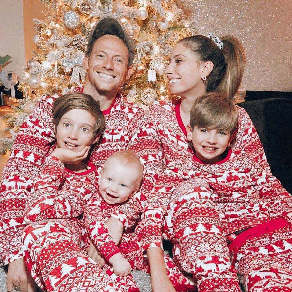 Famille assortie en pyjama de Noël rouge devant le sapin Image
