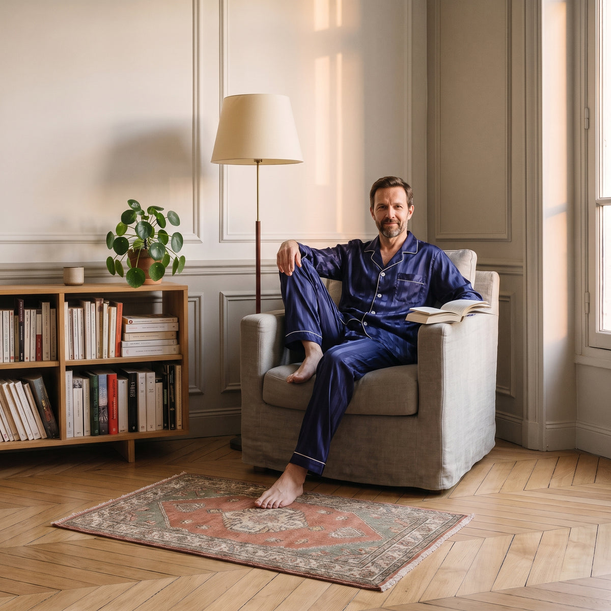 Homme du casting en pyjama bleu assis dans le fauteuil de lecture Image