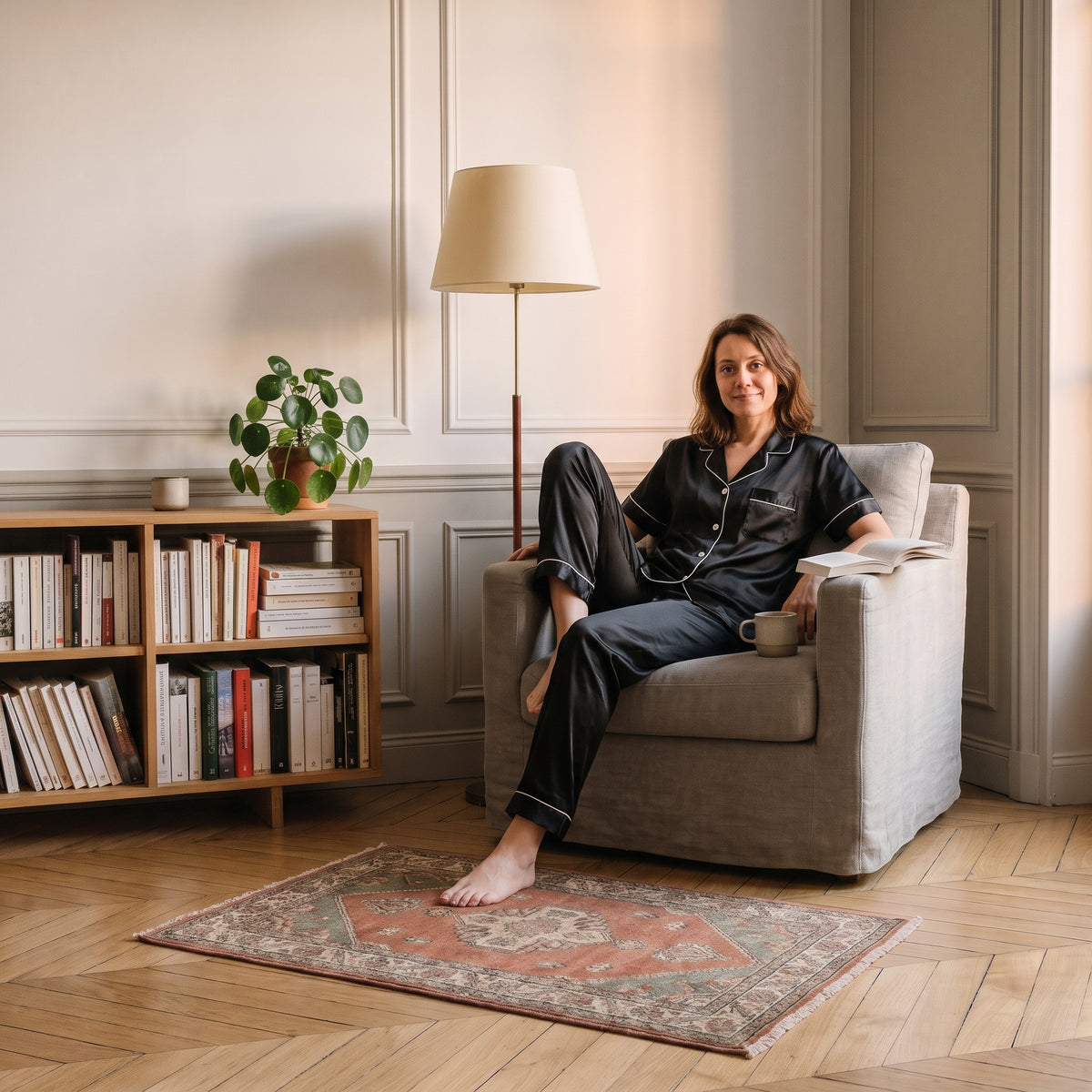 Femme du casting en pyjama satin noir, assise dans le coin lecture Image