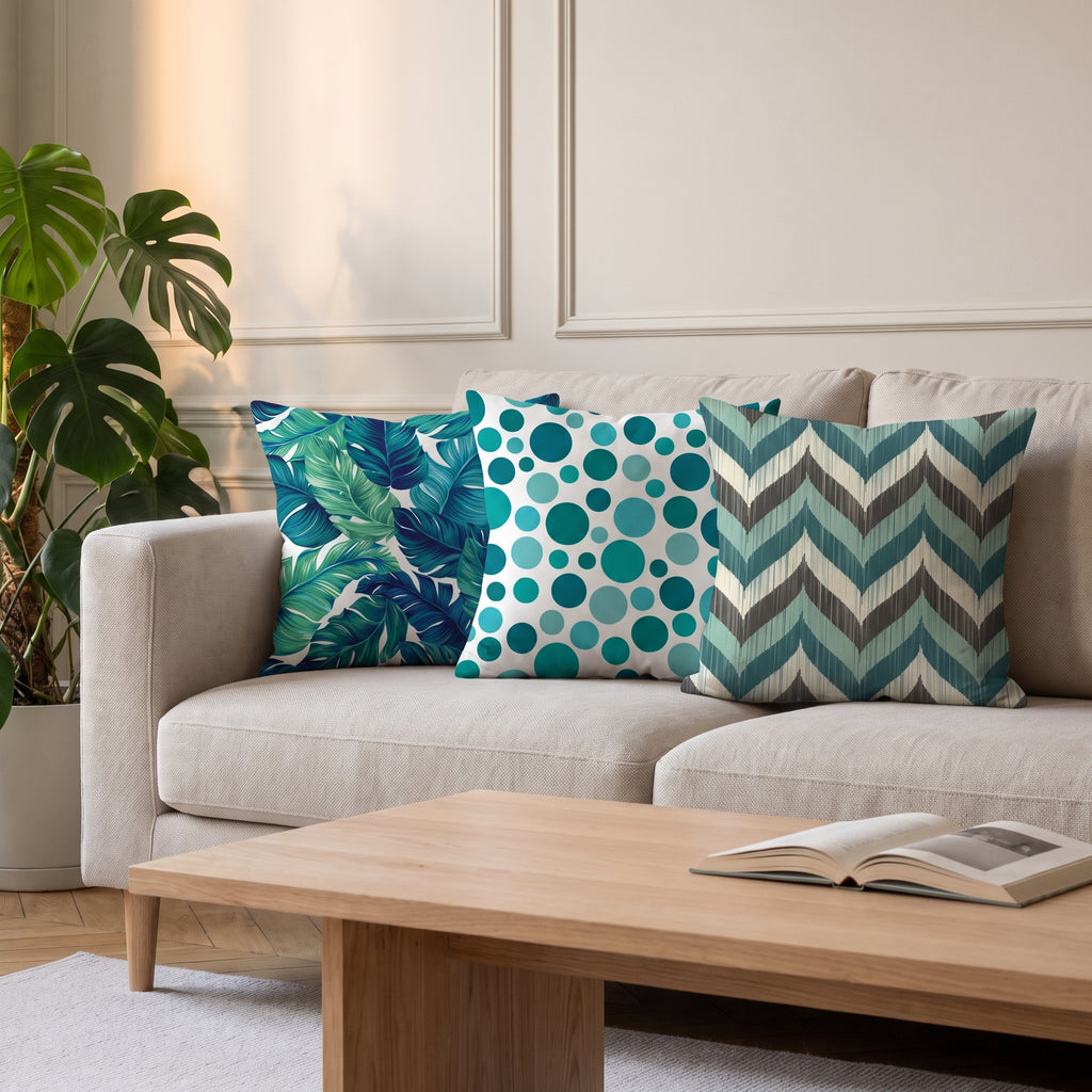 Trois housses de coussin à motifs verts et bleus posées sur un canapé de salon