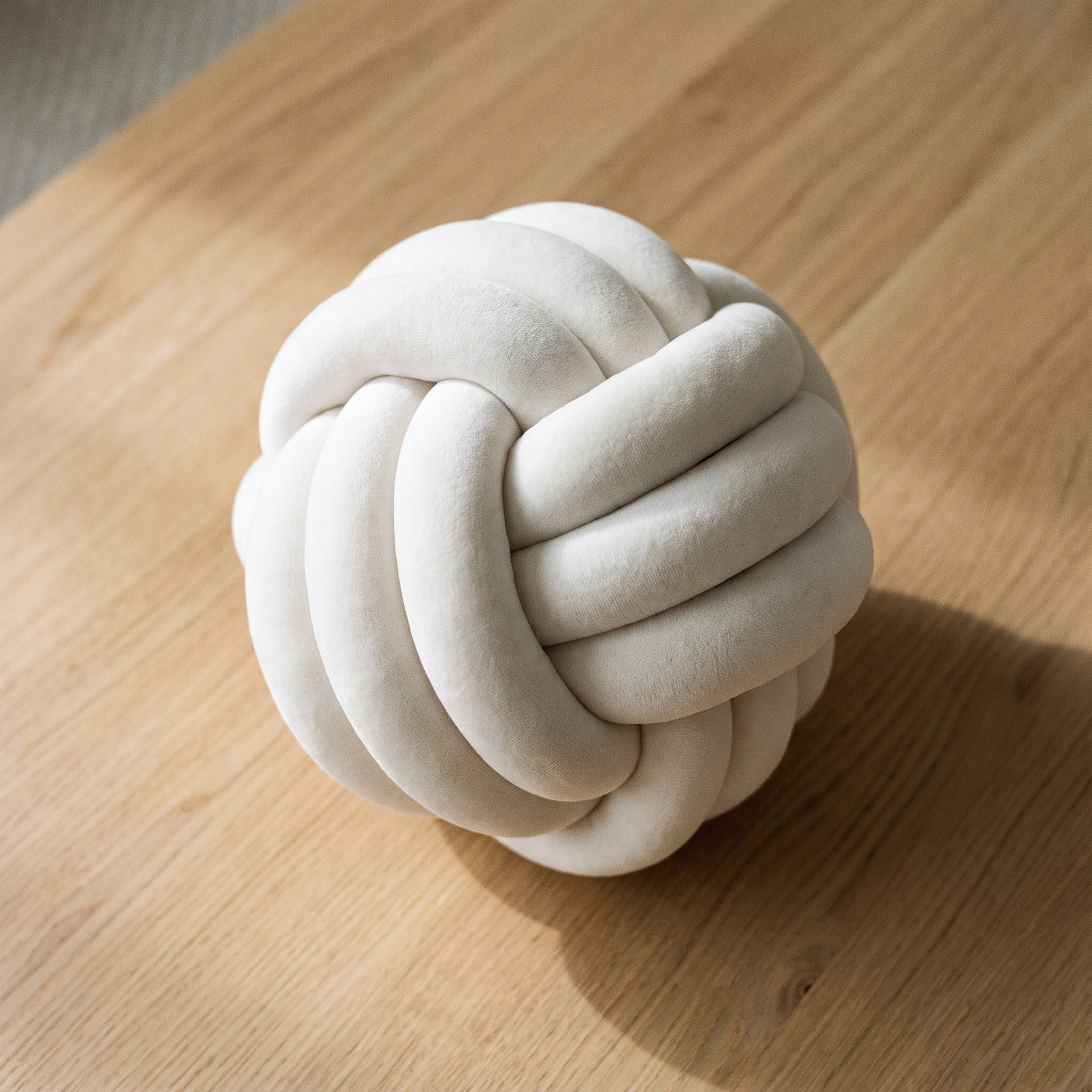 Coussin nœud blanc cassé vu de dessus, le tressage se referme au centre de la sphère Image