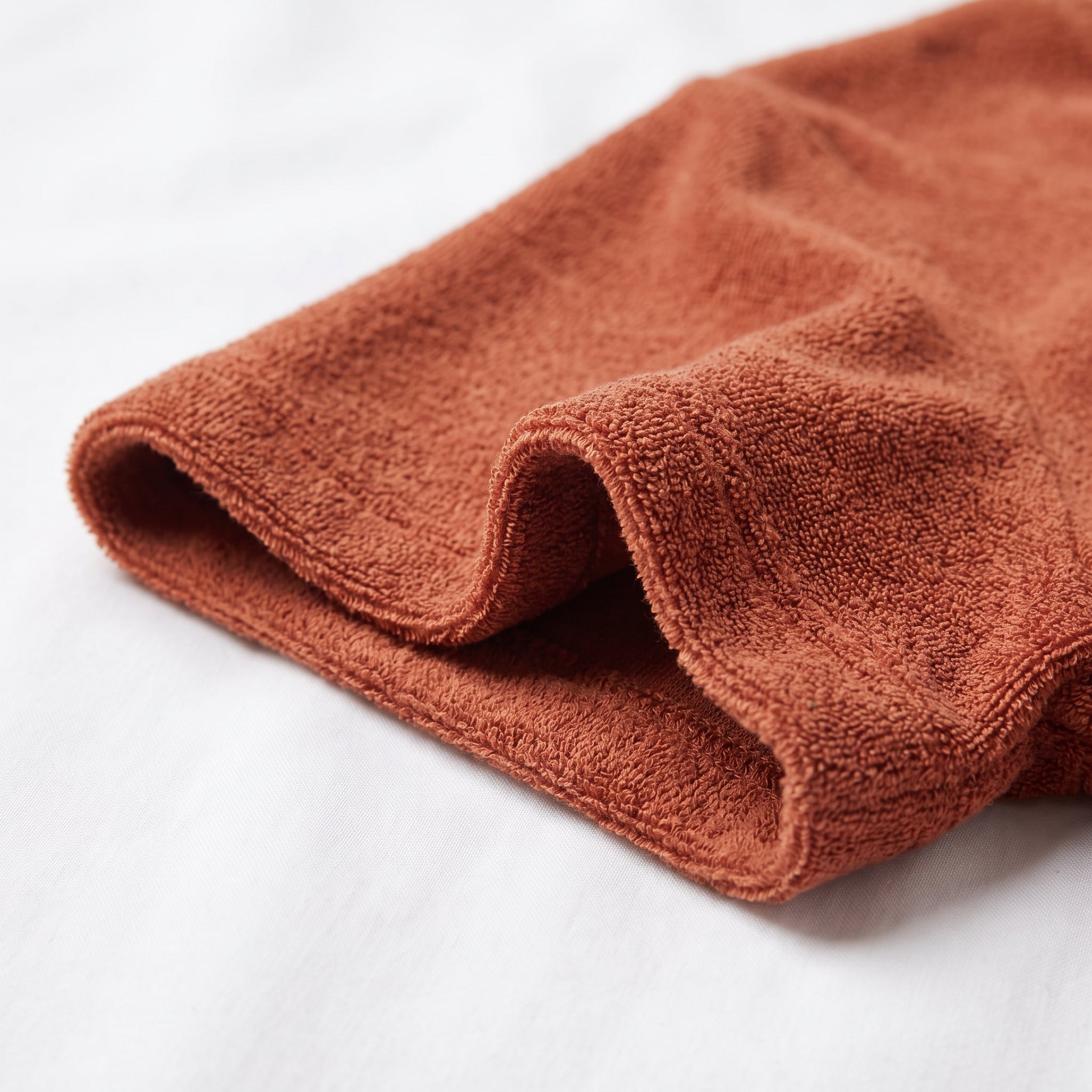 Manche de l'ensemble en éponge terracotta repliée sur un drap de coton blanc Image