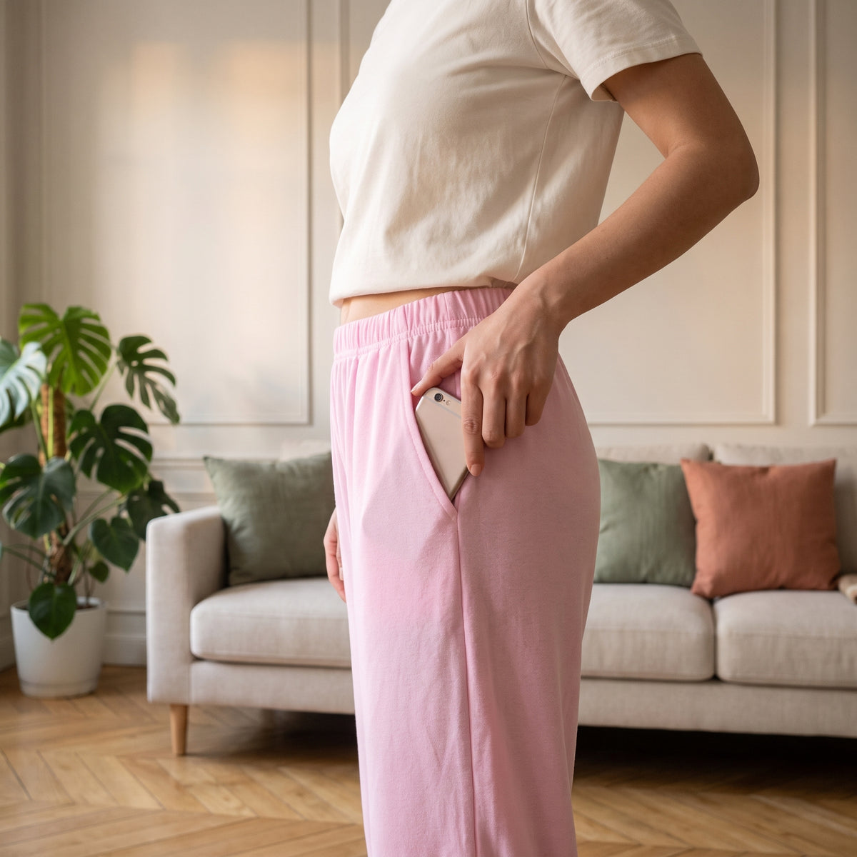Une main glisse un telephone dans la poche laterale du bas de pyjama rose, l ouverture part en biais sous la ceinture. Image