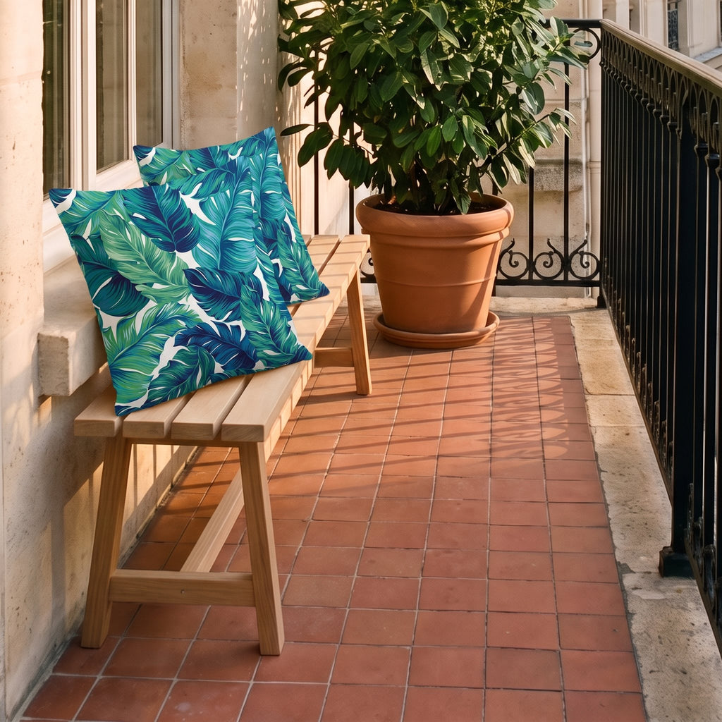 Deux housses de coussin à feuillage posées sur le banc d'un balcon
