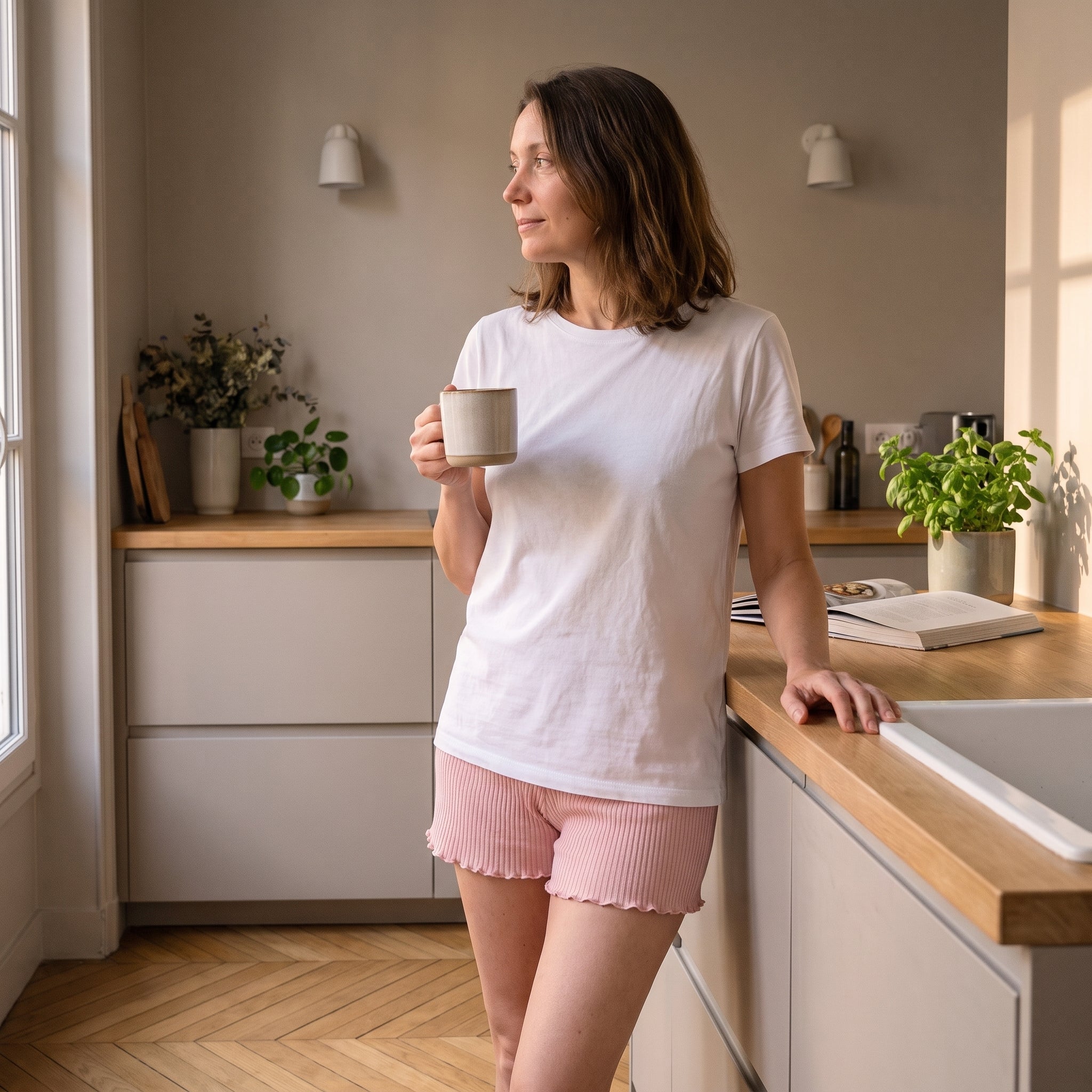 Femme en short boxer sous un tee-shirt ample, dans la cuisine le matin Image