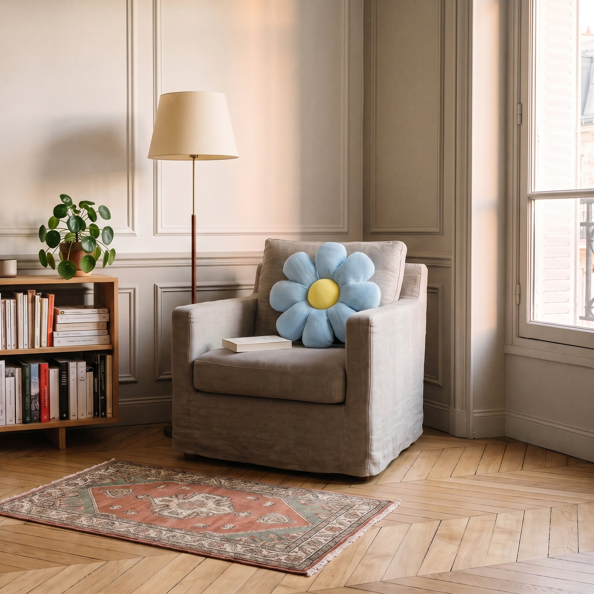 Coussin fleur bleu a huit petales pose sur un fauteuil clair dans un coin lecture
