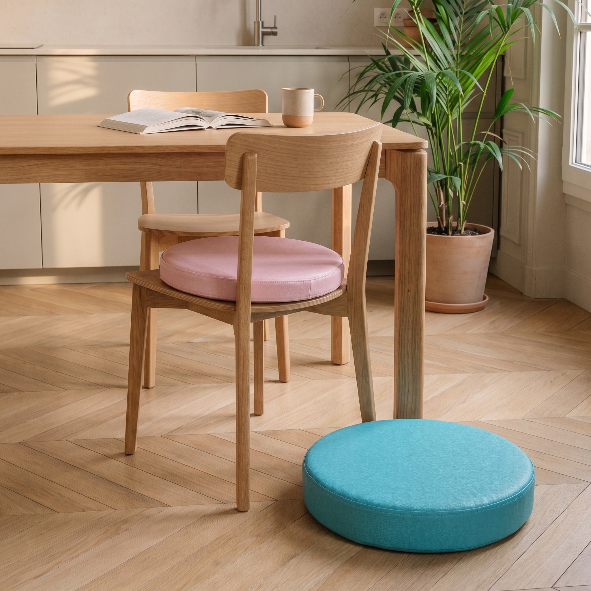 Coussin de sol rond rose posé sur l'assise d'une chaise en bois et coussin turquoise plus épais posé au sol à côté Image