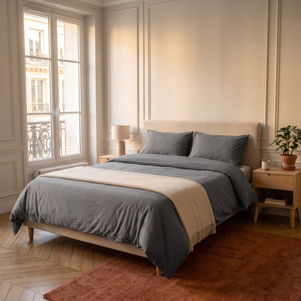 Chambre haussmannienne, lit fait avec la parure de lit reversible gris, unie sur ses deux faces, vue du pied du lit