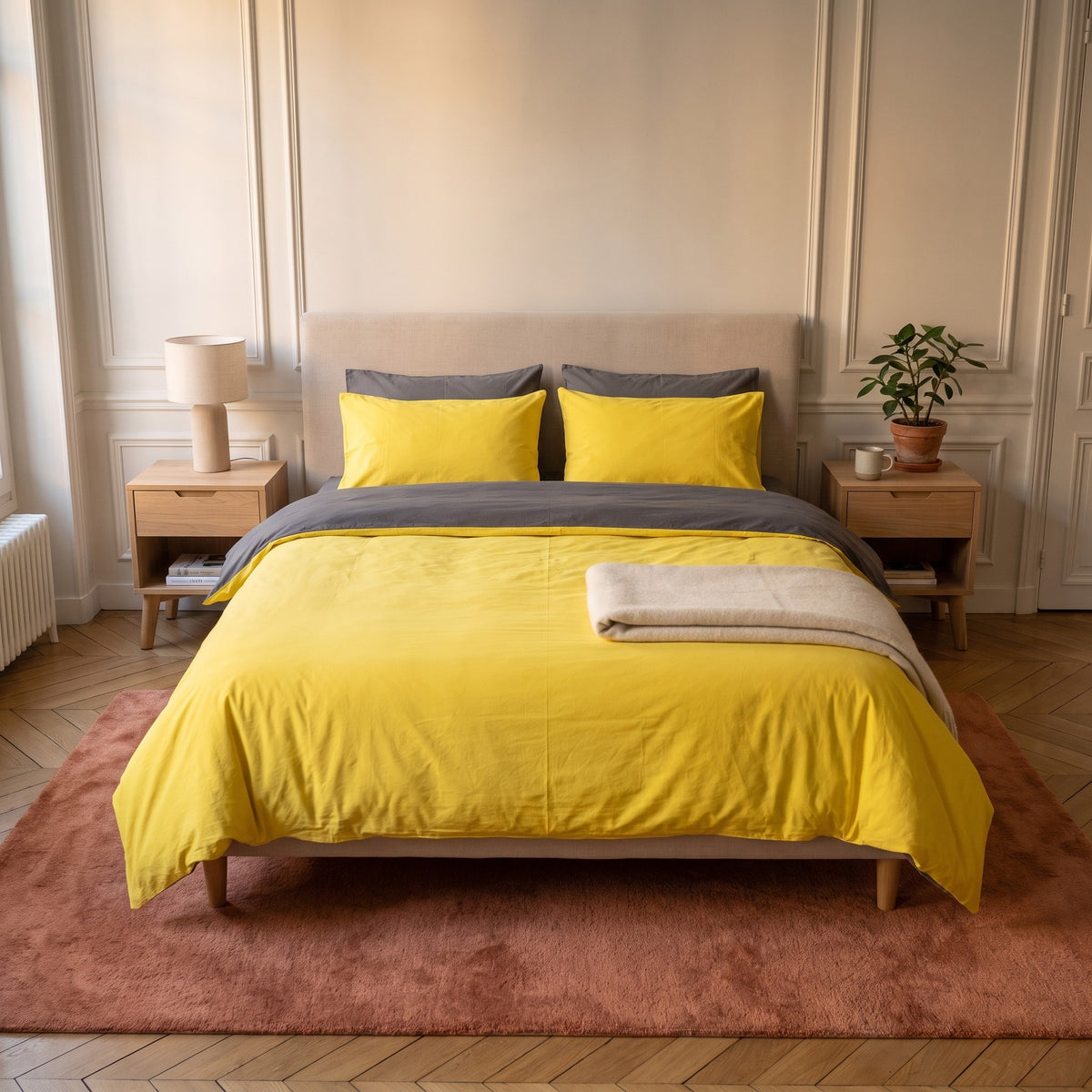 Chambre haussmannienne, lit fait avec la parure de lit reversible jaune et gris, le revers rabattu en tete de lit, vue du pied du lit
