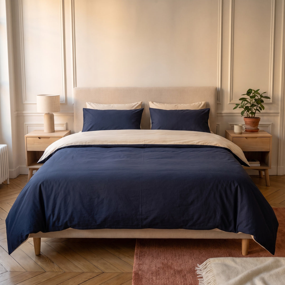 Chambre haussmannienne, lit fait avec la parure de lit reversible bleu foncé et beige, le revers rabattu en tete de lit, vue du pied du lit