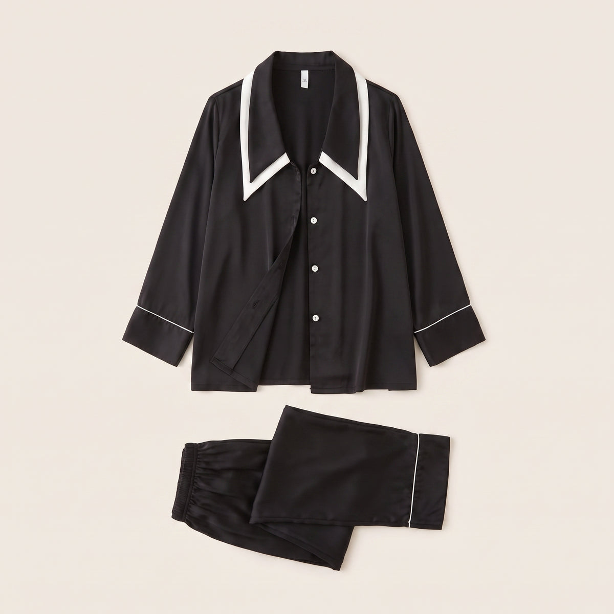 Pyjama en satin noir à liseré blanc, chemise et pantalon posés à plat
