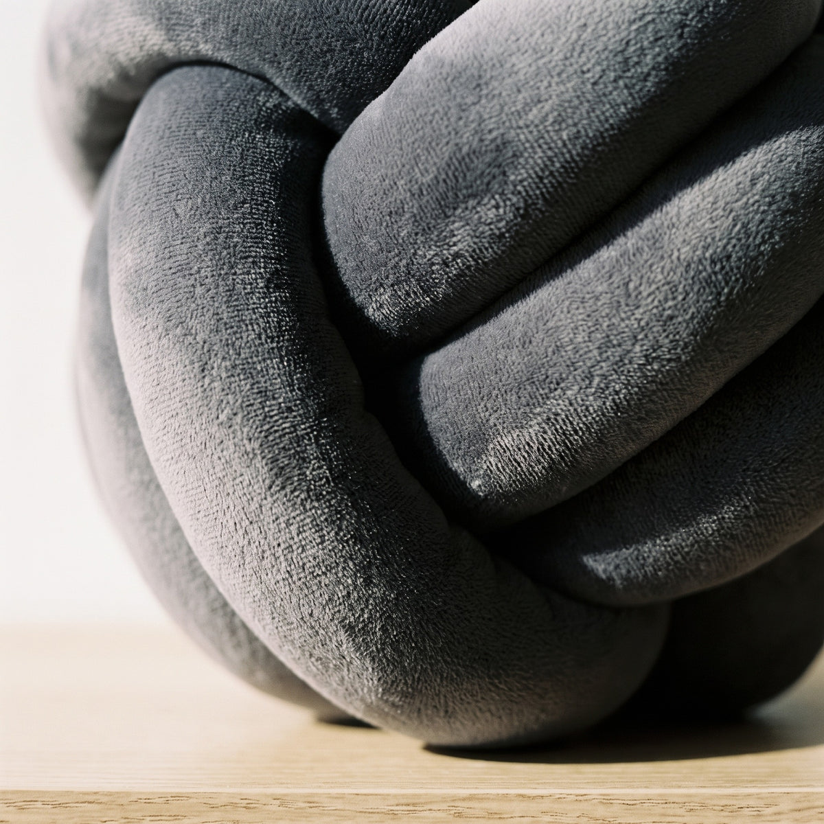 Gros plan sur le croisement des brins d'un coussin nœud gris foncé, velours à poil court