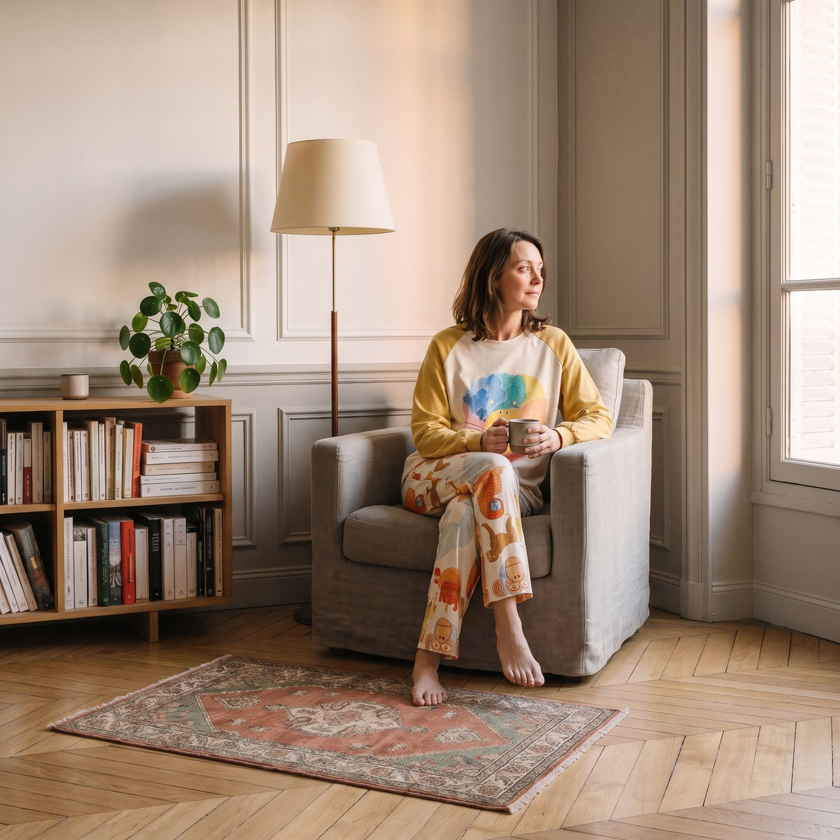 Femme en pyjama assise dans un fauteuil de lecture, une tasse à la main Image