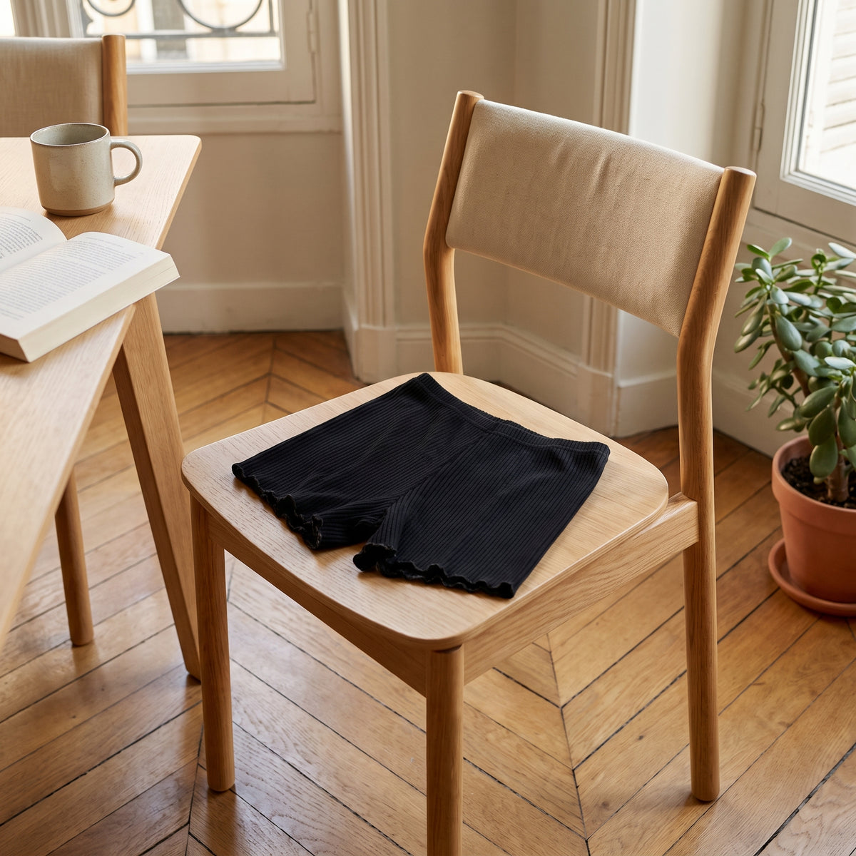 Short boxer noir pose deplie sur une chaise en bois clair