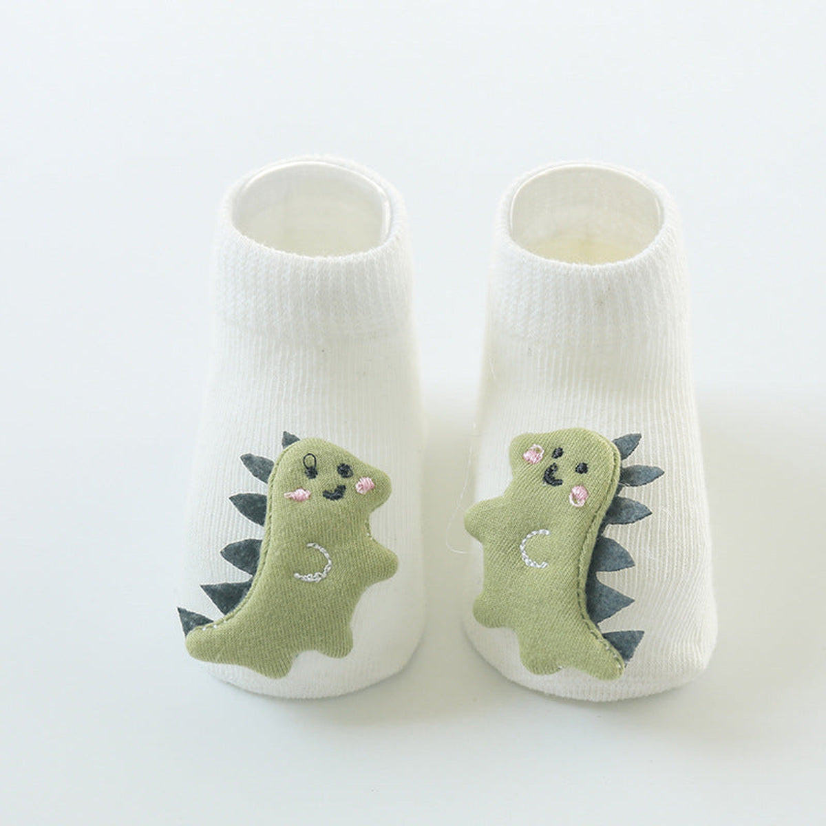Une paire de chaussettes antidérapantes bébé, motif dinosaure