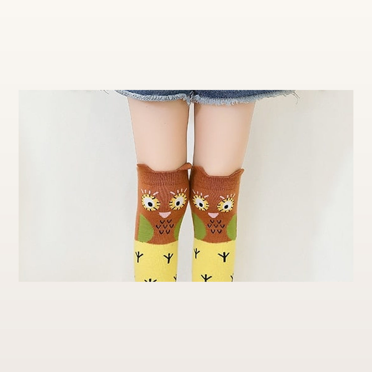 Gros plan sur les deux chouettes d'une paire de chaussettes enfant jaunes Image