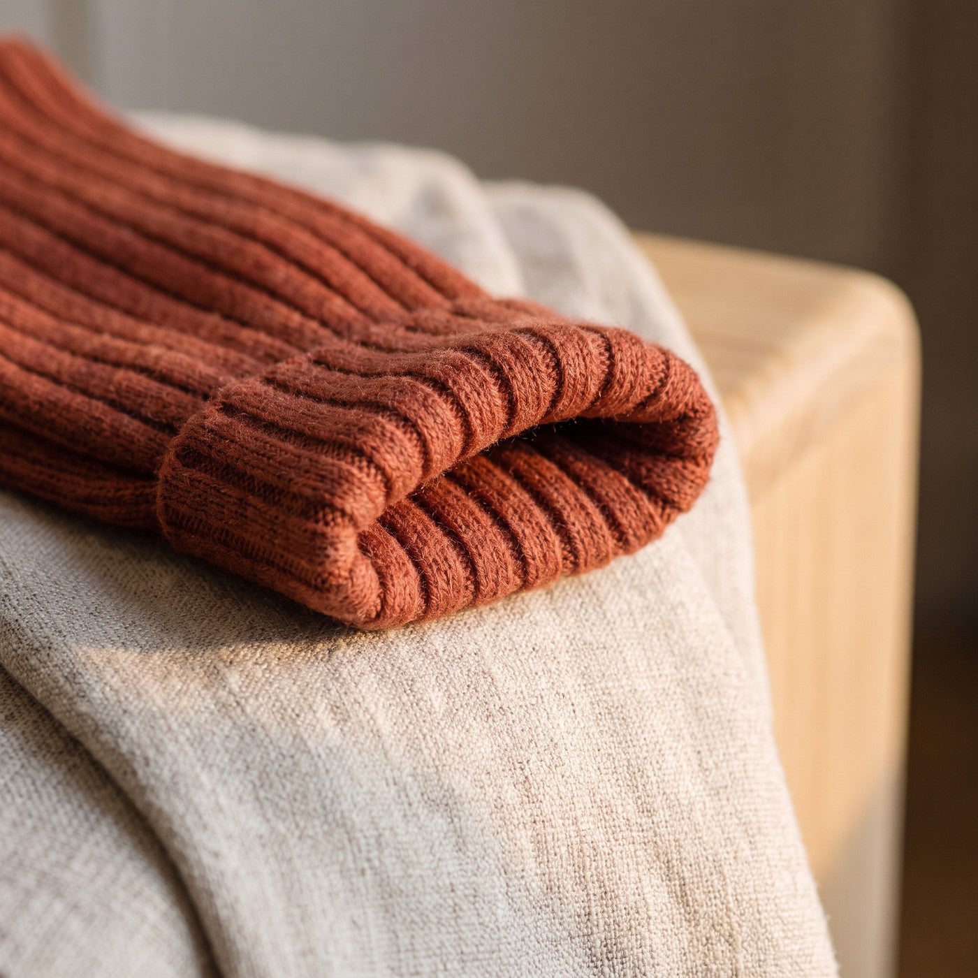 Gros plan sur la côte large et le bord souple d'une chaussette terracotta posée sur un plaid de lin Image