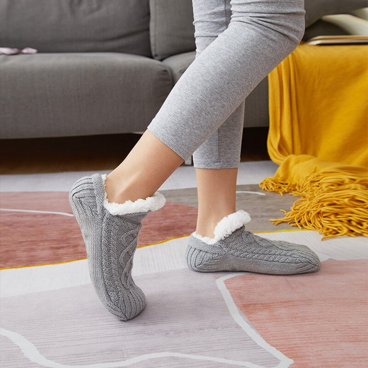 Chaussettes fourrées grises à maille torsadée portées dans un salon