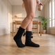 Chaussettes fourrées noires à pompons portées sur le parquet du coin repas