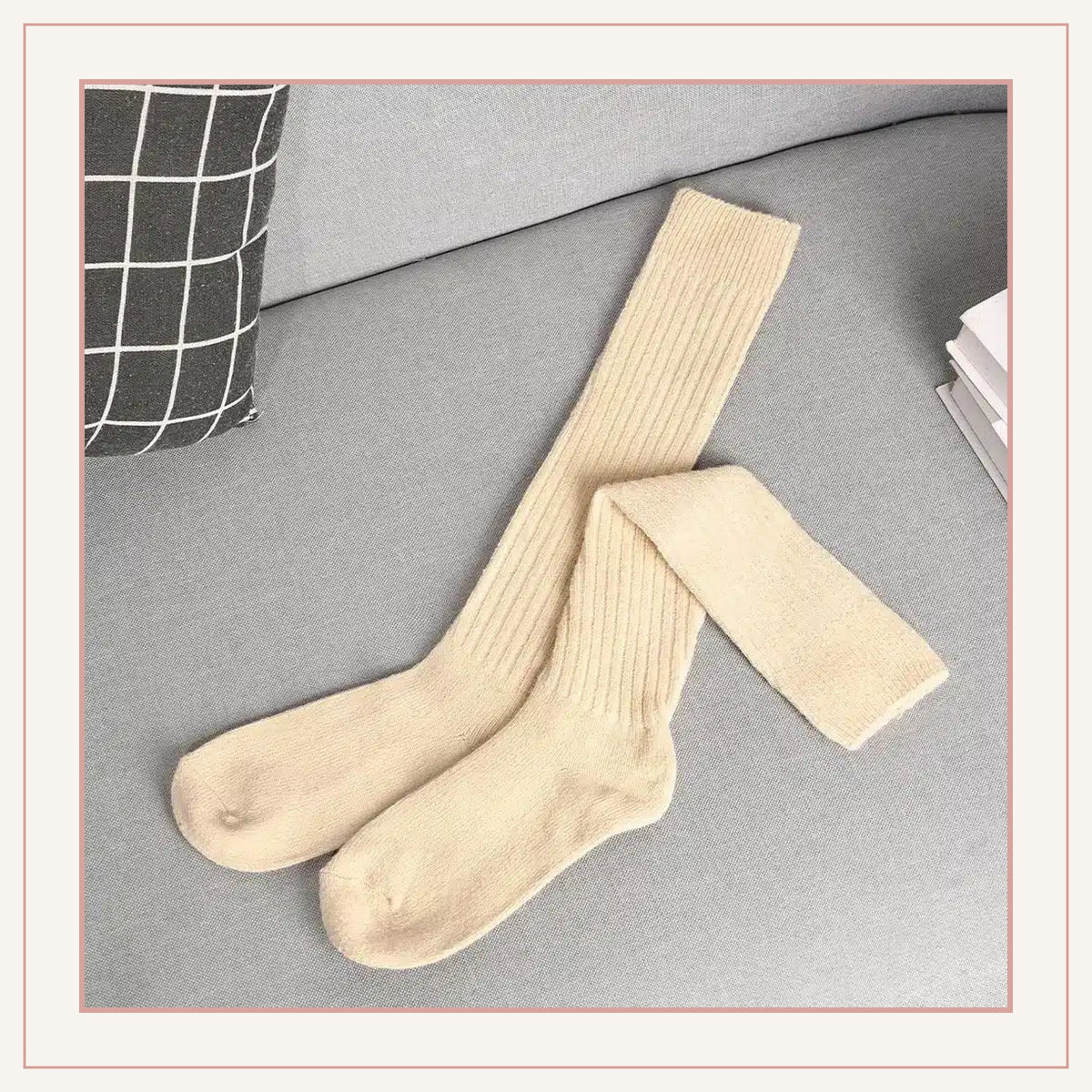 Paire de chaussettes hautes côtelées beige posée sur un canapé
