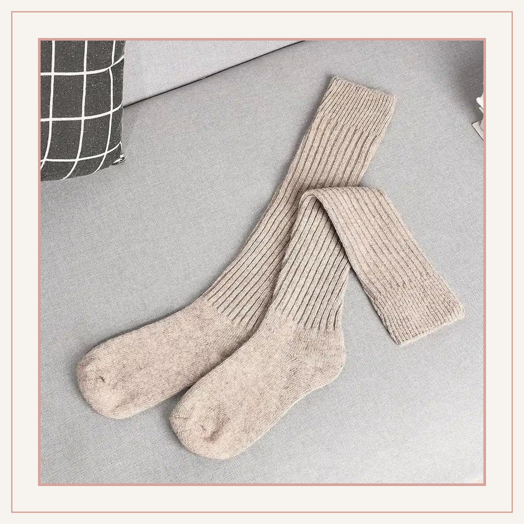 Paire de chaussettes hautes côtelées marron clair posée sur un fauteuil